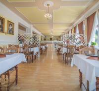 A hall with a wooden floor decor, set tables, and paintings on the walls. Hotels and guesthouses.