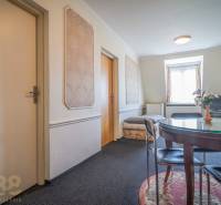 Interior of a hotel and guesthouse with a round table, carpet, TV, and decorative walls.