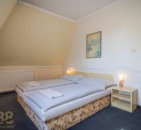 A room with a double bed, a nightstand, a painting, a lamp, carpets in hotels and guesthouses.