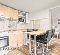 A kitchen in a family house with a bar table, black chairs, and a wooden decor floor.