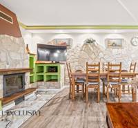 Interior of a family house with a fireplace, stone wall, dining table, and floor with wood decor.