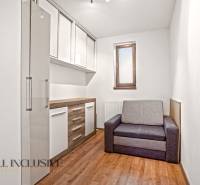 A room in a family house with a wooden decor floor, a gray sofa, and storage cabinets.