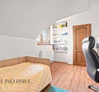 A room in a family house with a bed, shelves, a table, and a floor with a wooden decor.