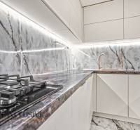 A family house kitchen with a marble wall, gas stove, and sink.