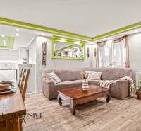Living room in a family house with a wooden decor floor and green details on the ceiling.