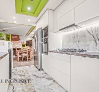 Kitchen of a family house with white cabinets, stone countertop, and decorative ceiling.