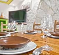 A dining table set in a family house with a wooden decor floor and a stone wall.