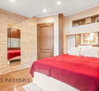 Bedroom in a family house with a bed, stone details, and a wooden decor floor.