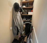 Storage space with clothing, hats, shoes, and a vacuum cleaner in a studio apartment.