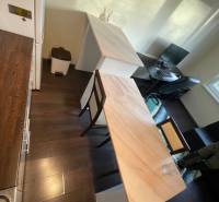 A kitchen in a studio apartment with a wooden floor decor, a bar counter, and a work desk.