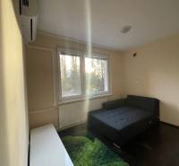 A simple room with a bed, carpet, and window in a studio apartment.