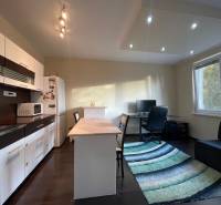 A kitchen in a studio apartment with a wood-patterned floor and a work corner.