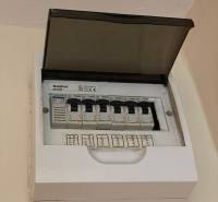 An electrical panel with an open cover and labeled circuit breakers in a studio apartment.