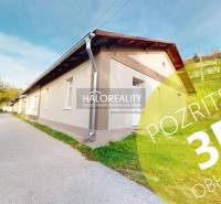 A family house in Sirk with a long facade, green lawn, and an access road on the side.