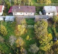 A family house in Sirk, surrounded by greenery and trees, with single-story buildings.