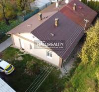 A family house in Sirk with a metal roof and a car on the grassy garden.