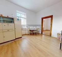 Interior of a family house with a wooden decor floor, a cabinet, and a table with two chairs.