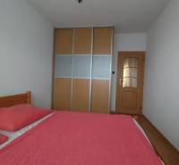 A bedroom in a 3-room apartment with a bed and a wardrobe with sliding doors.