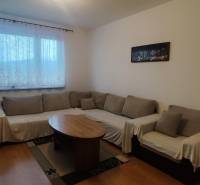 Living room in a three-room apartment with a corner sofa, wooden decor flooring, coffee table.