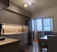 A kitchen with a wooden decor floor and a dining table in a 3-room apartment.