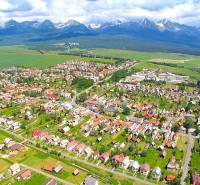 Aerial view of agricultural and forest land in Štrba with the High Tatras in the background.