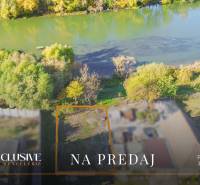 Land for sale by the river in Jahodná, surrounded by greenery and trees.