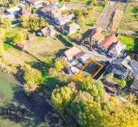 Aerial photograph of residential plots in Jahodná near a body of water surrounded by greenery.