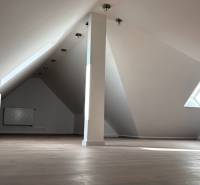 Attic space in a 3-room apartment with a window and a floor with a wooden decor.