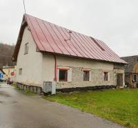 A family house in Kolárovice with a red roof by the road and a green lawn.