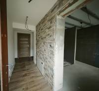 A hallway with a stone-decorated wall and a wood-decorated floor in a family house.