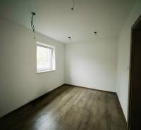 A room in a family house with white walls and a wooden decor floor.