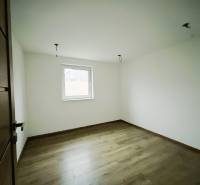 A room in a family house with white walls and a wooden decor floor.