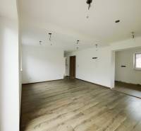 A spacious room in a family house with a wooden decor floor and white walls.