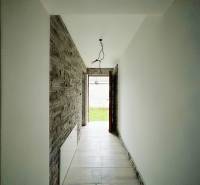 A hallway of a family house with stone cladding and a view of the garden.