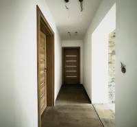 A hallway in a family house with doors in a wooden decor and white walls.