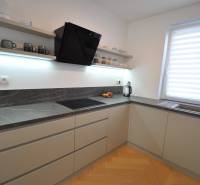 A kitchen in a family house with a dark countertop and a floor with a wood decor.