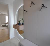 Interior of a family house with a wooden decor floor, a mirror, and houseplants.