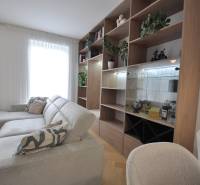 Living room in a family house with a white couch, wooden bookshelf, and plants.