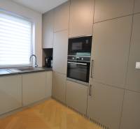 A kitchen in a family house with a wood-patterned floor and built-in appliances.