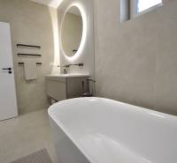 A bathroom in a family house with a freestanding bathtub and an oval mirror.