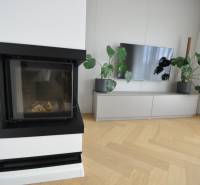 Living room in a family house with a fireplace, television, and wooden decor flooring.