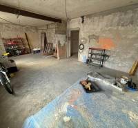 An unfinished room in a family house with a bicycle and shelves for various tools.