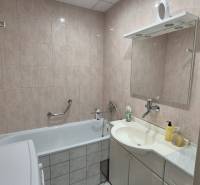A bathroom with a bathtub, sink, and mirror in a three-room apartment.