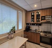 A kitchen in a 3-room apartment with a gas stove, cabinets, and a dining table.