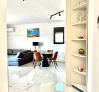 Interior of a 1-room apartment with a white floor, gray sofa, and dining table.