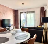 Living room in a one-room apartment with a television, balcony, and an elegant table.