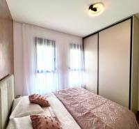 A room with light furniture and decorative pillows in a studio apartment.