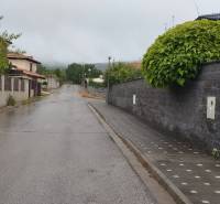 A rainy alley in Limbach surrounded by properties - residential, with fences and greenery.