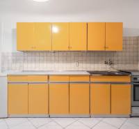 A kitchen in a 3-room apartment with orange cabinets and white tiles.