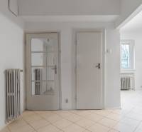 Interior of a 3-room apartment with white doors, a mirror, a radiator, and tiles.
